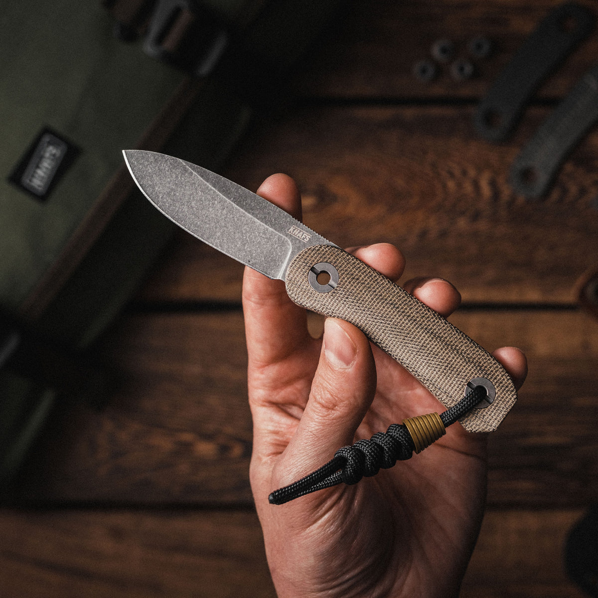 Lander 4 Fixed Blade Knife in Moondust Micarta held in hand, close-up of the blade