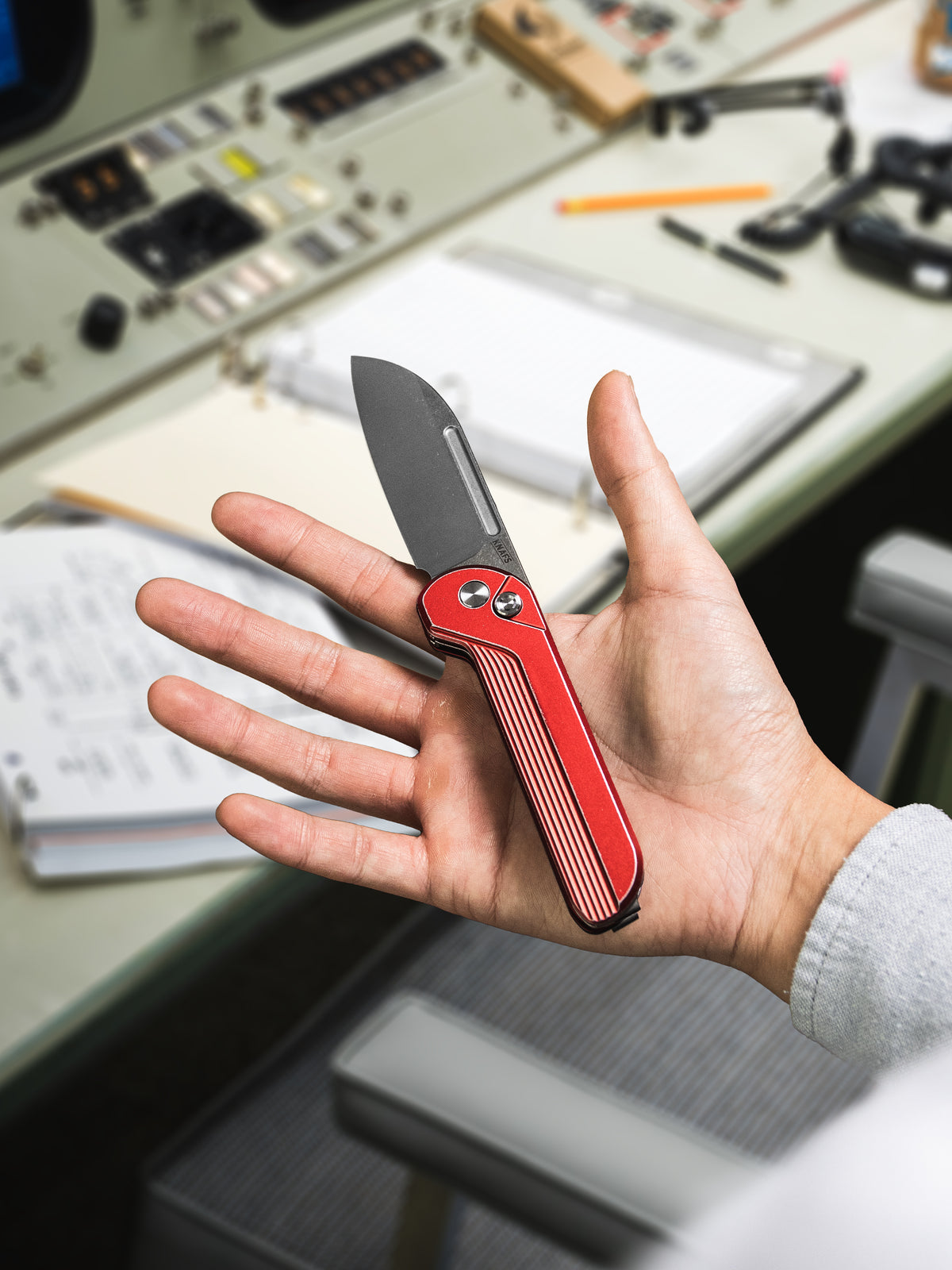 Hand holding open Capcom pocket knife with Re-Entry Red handle