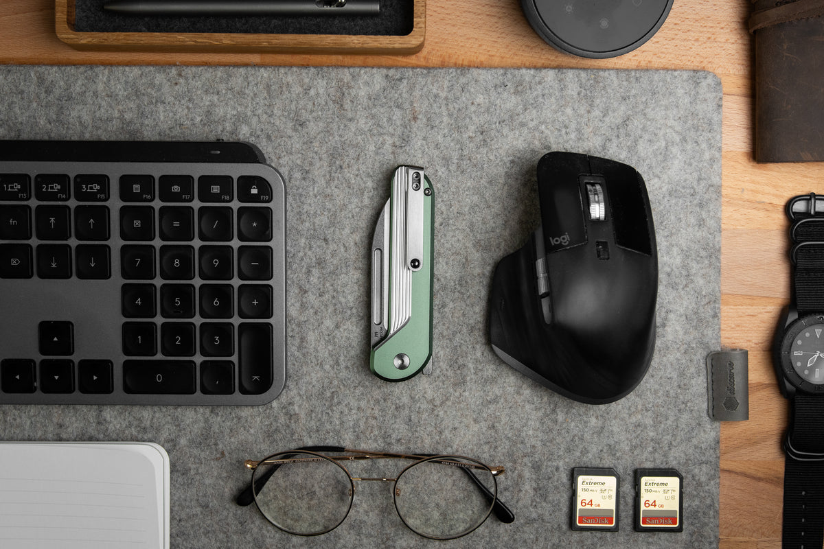 Capcom pocket knife with Mission Control green handle on desk with mouse and glasses