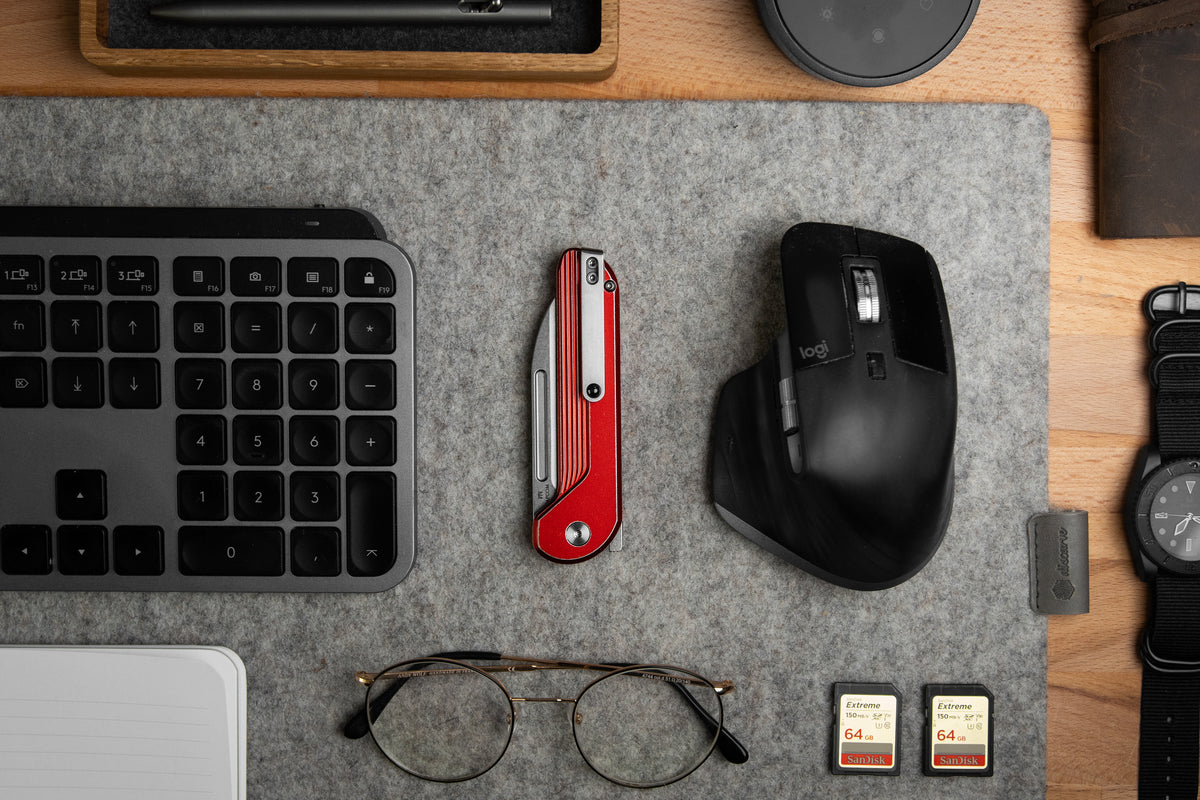 Capcom pocket knife with Re-Entry Red handle on desk with mouse and glasses