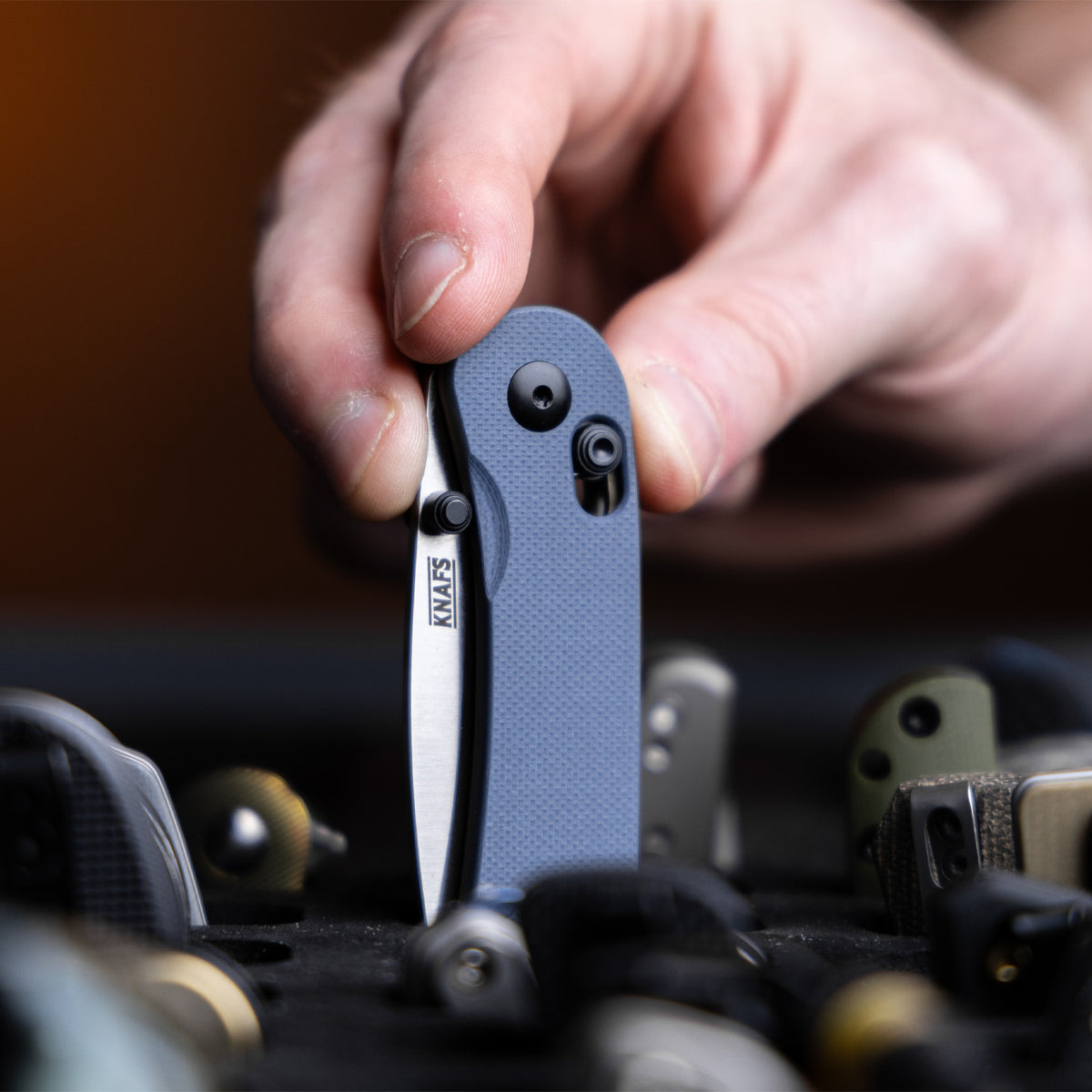 Lander 3 Pocket Knife in Horizon Blue G10 held near a laptop keyboard, close-up