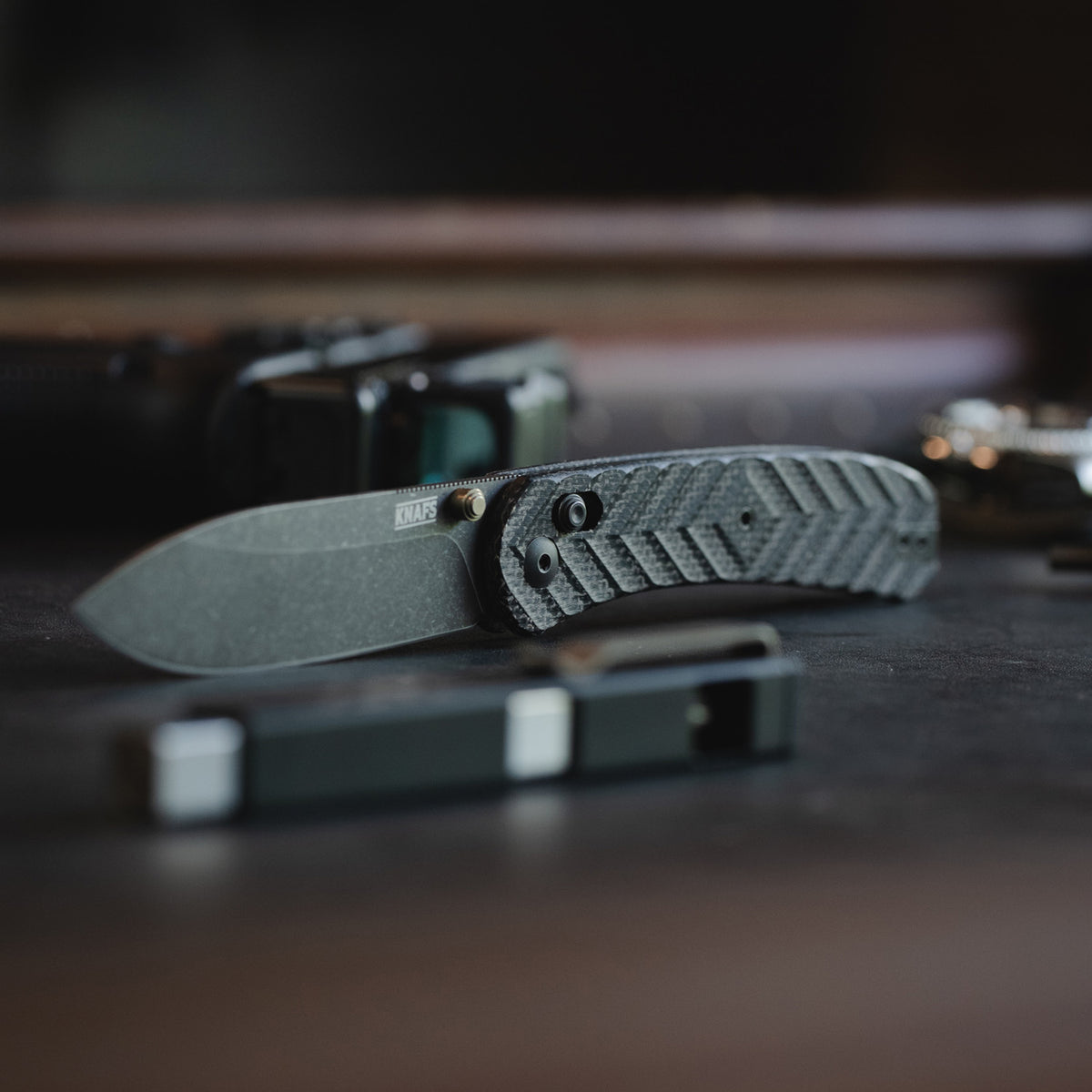 Tattooed man holding Jeremy Siers Lander 2 knife with black micarta handle up to camera