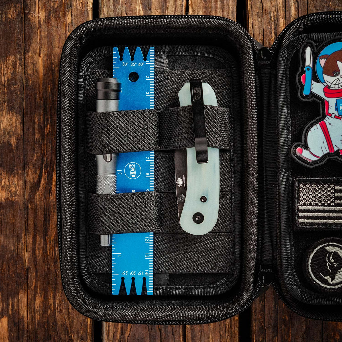 Knafs x Vault Case NANO Knife EDC Case, open and filled, flat lay on a wood table