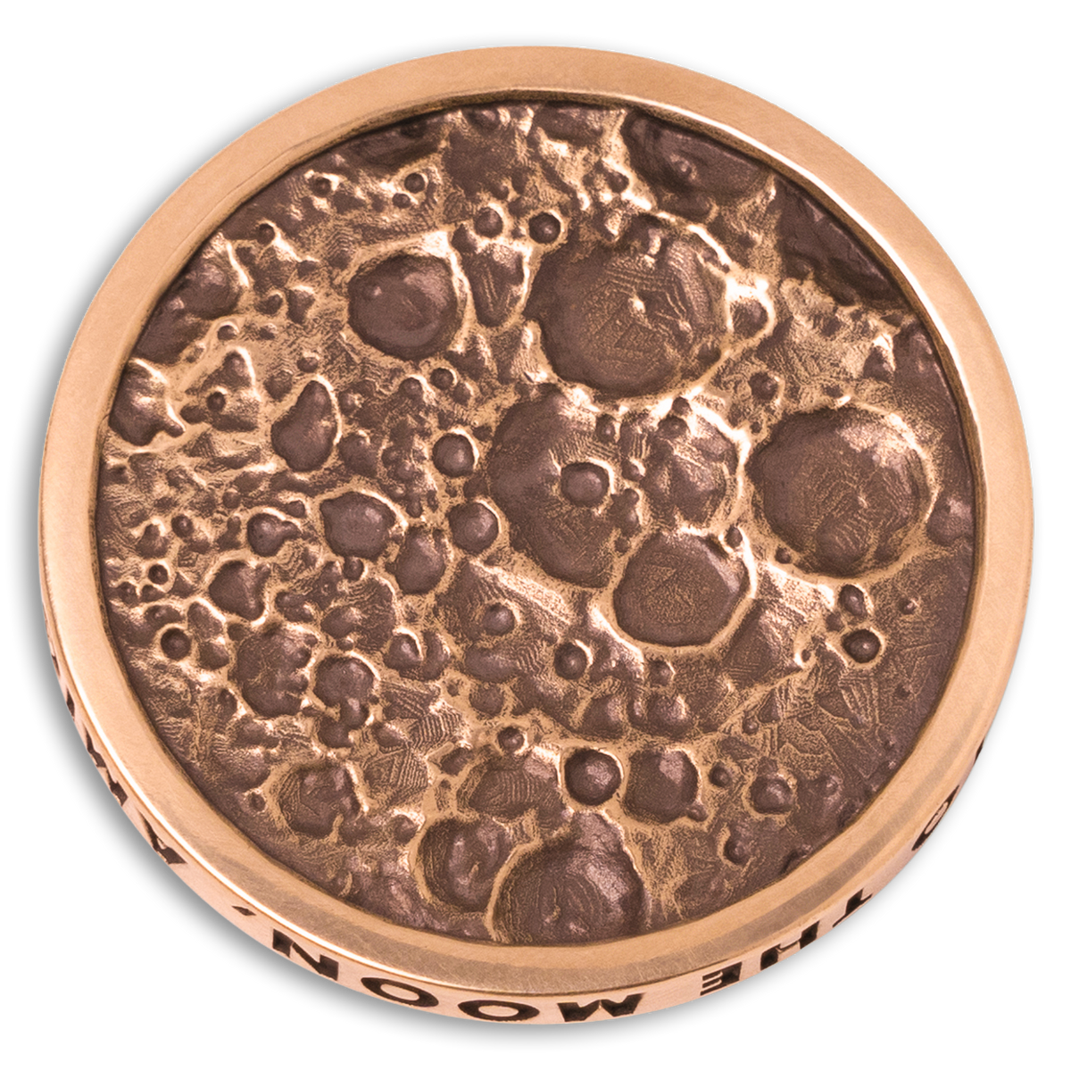 A circular bronze-colored metal coin or medallion with a textured, crater-like surface resembling the moon, shown on a plain white background. Part of the text 'THE MOON' is visible along the lower rim.