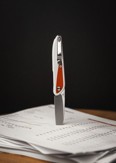 Doodler pen with white and red handle resting on papers on wood desk