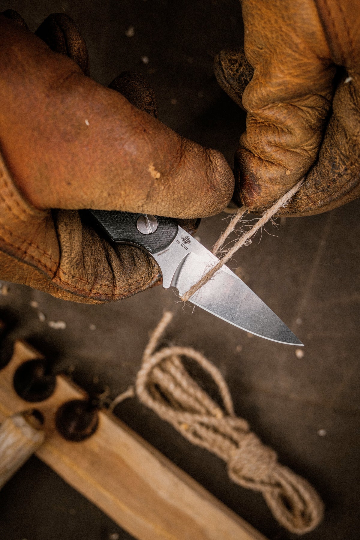 Little Lulu fixed blade knife with black micarta handle cutting cordage outdoors, close-up