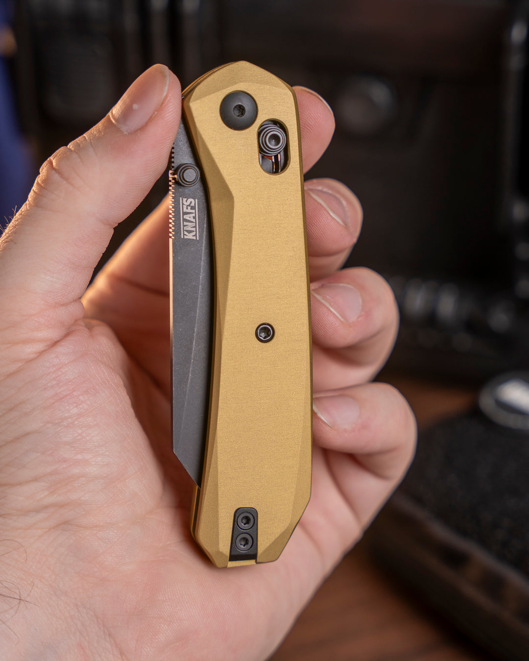 Hand holding closed Lander 2 Reverse Tanto pocket knife with gold aluminum handle