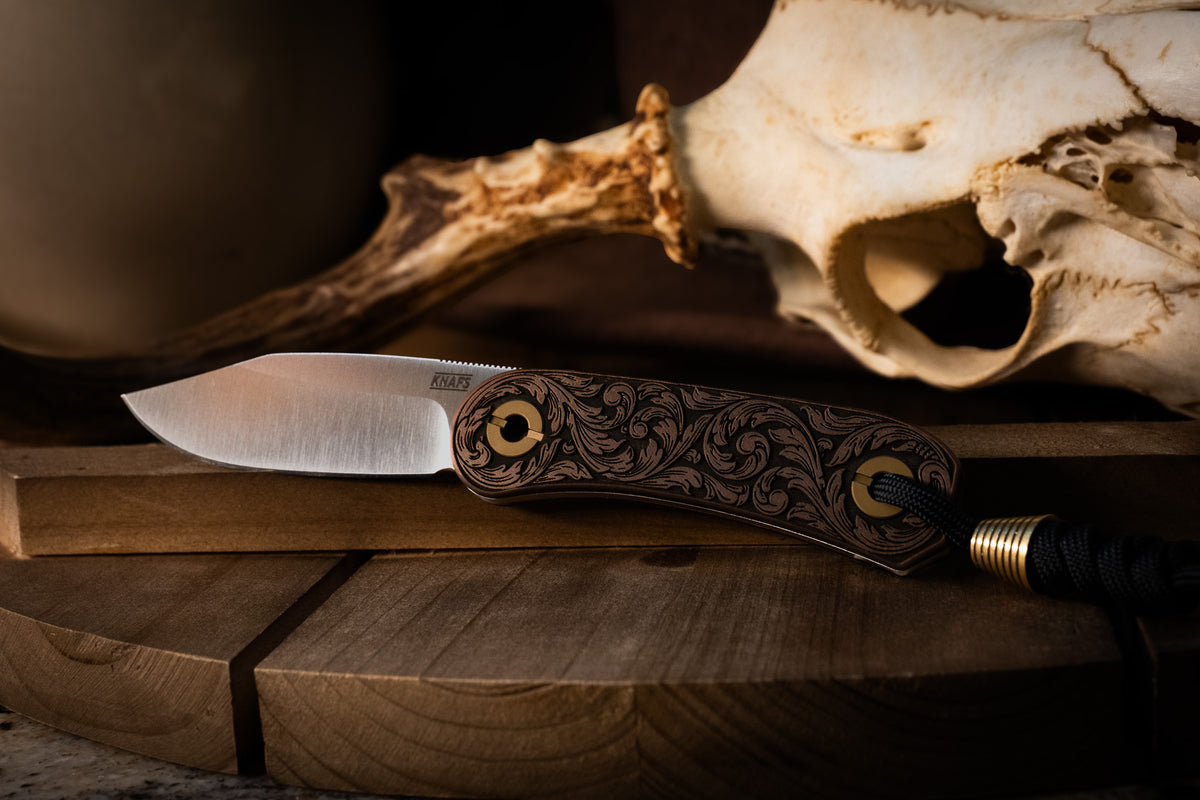 Lander 4 pocket knife with filigree engraved handle resting near animal skull outdoors