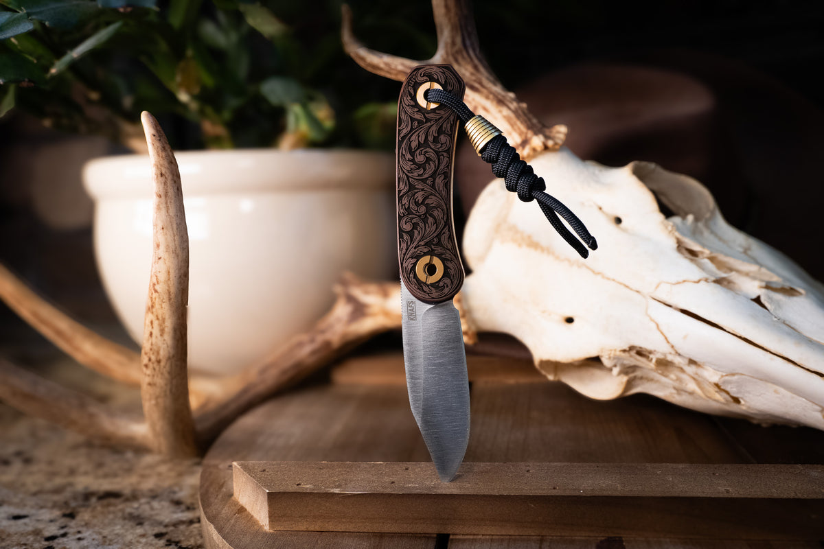 Lander 4 pocket knife with filigree engraved handle displayed with antlers and skull decor