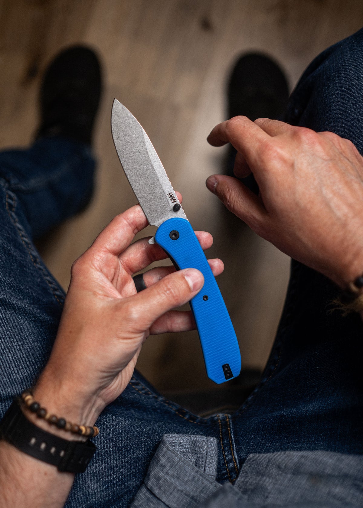 Hand holding closed Lander 7 pocket knife with blue G10 handle outdoors