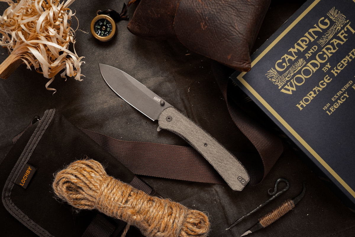 Lander 7 pocket knife with Moondust micarta handle beside leather journal and twine outdoors