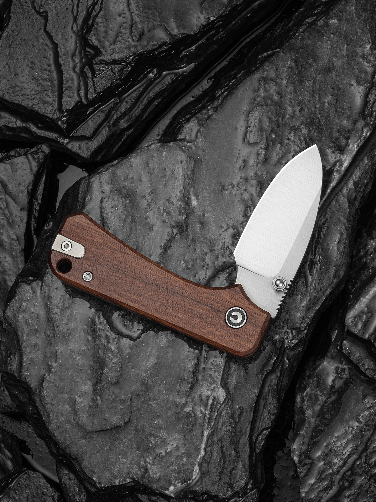Baby Banter slip joint knife with brown wood handle, open, resting on dark stone surface