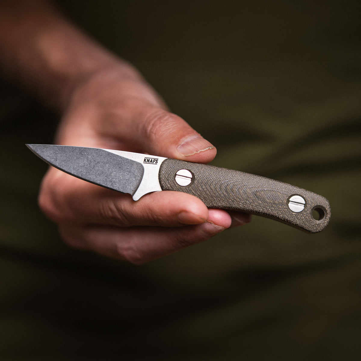 Hand holding Little Lulu stonewashed fixed blade knife, front view