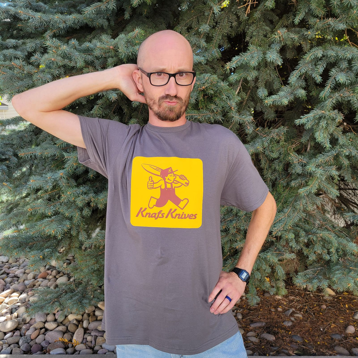Man standing outdoors wearing Knafs Blade Show West 2025 t-shirt, side angle