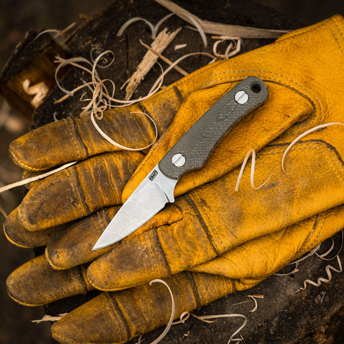 Little Lulu fixed blade knife with green Micarta handle held in a tan leather work glove, blade exposed