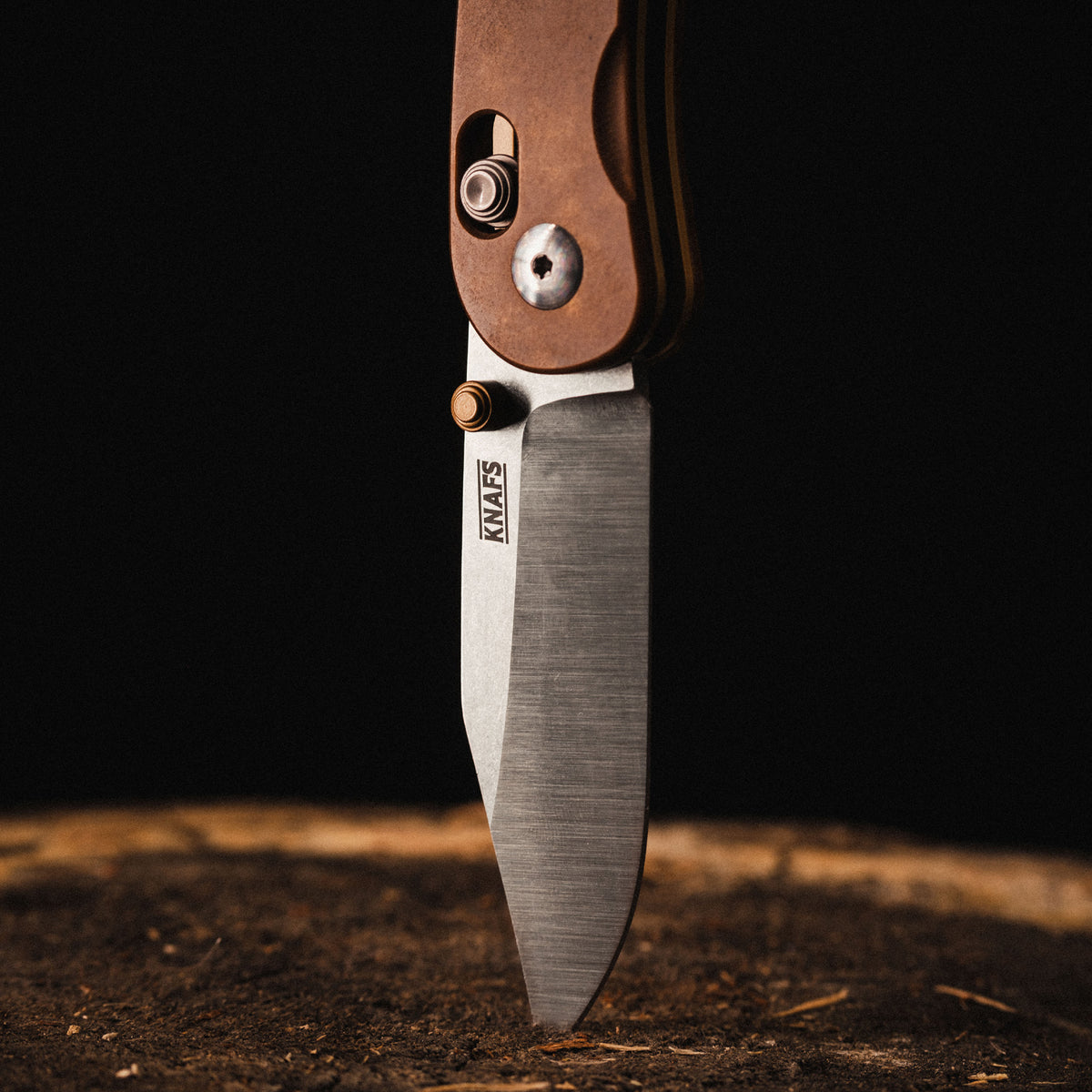 Lander 3 pocket knife blade tip embedded in wood, close-up