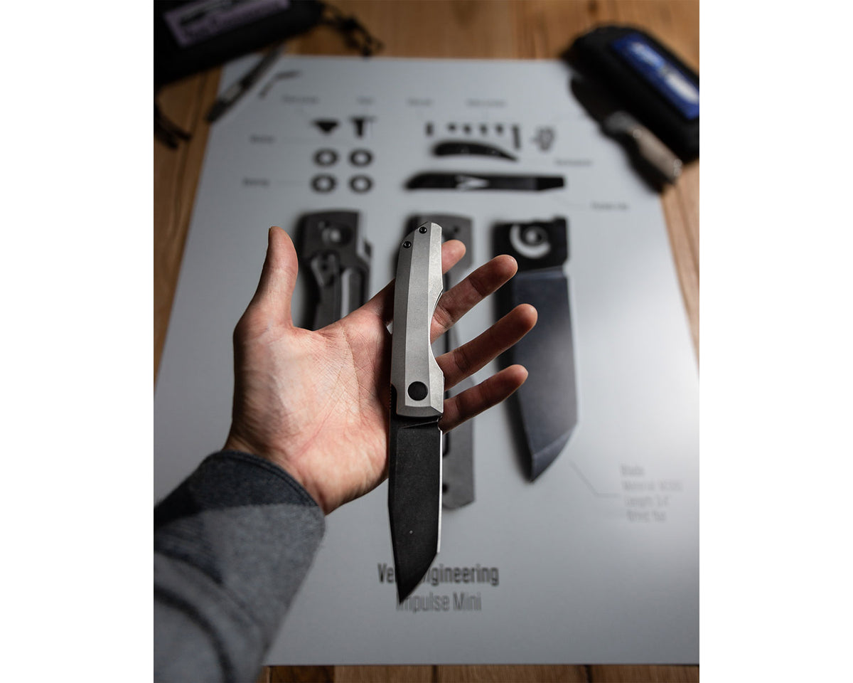 Vero Engineering Knife Poster "Impulse" in a flat lay surrounded by pocket knives