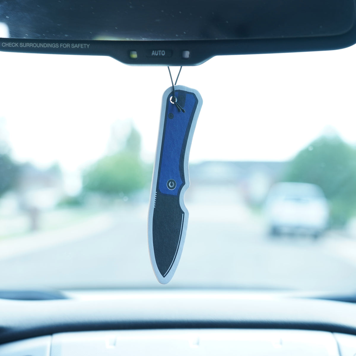 CIVIVI Knife Air Freshener hanging from a rearview mirror, viewed through the windshield while driving