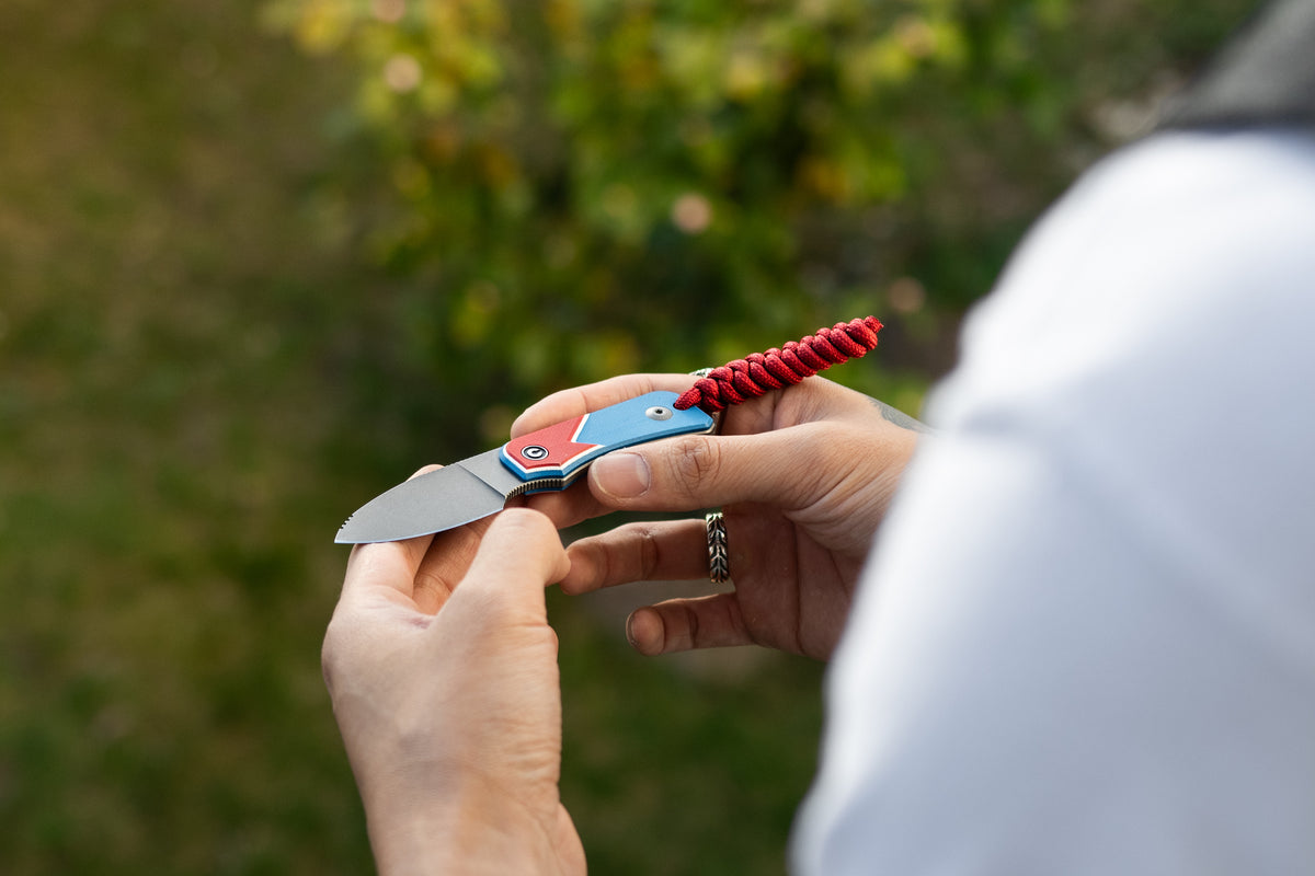 Hand holding open Baby Banter fixed blade knife, Jump Edition, outdoors