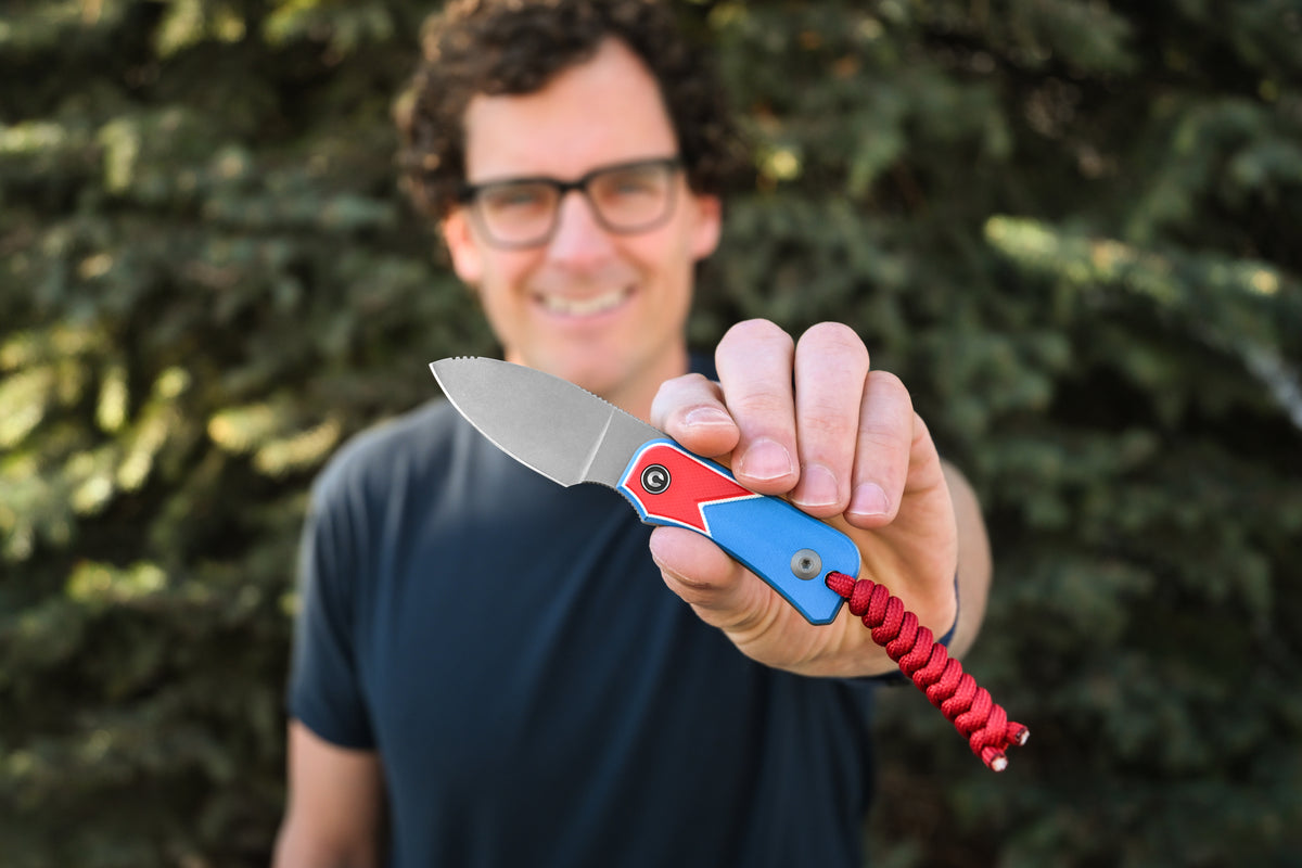 Smiling man wearing glasses holding Baby Banter fixed blade knife, Jump Edition