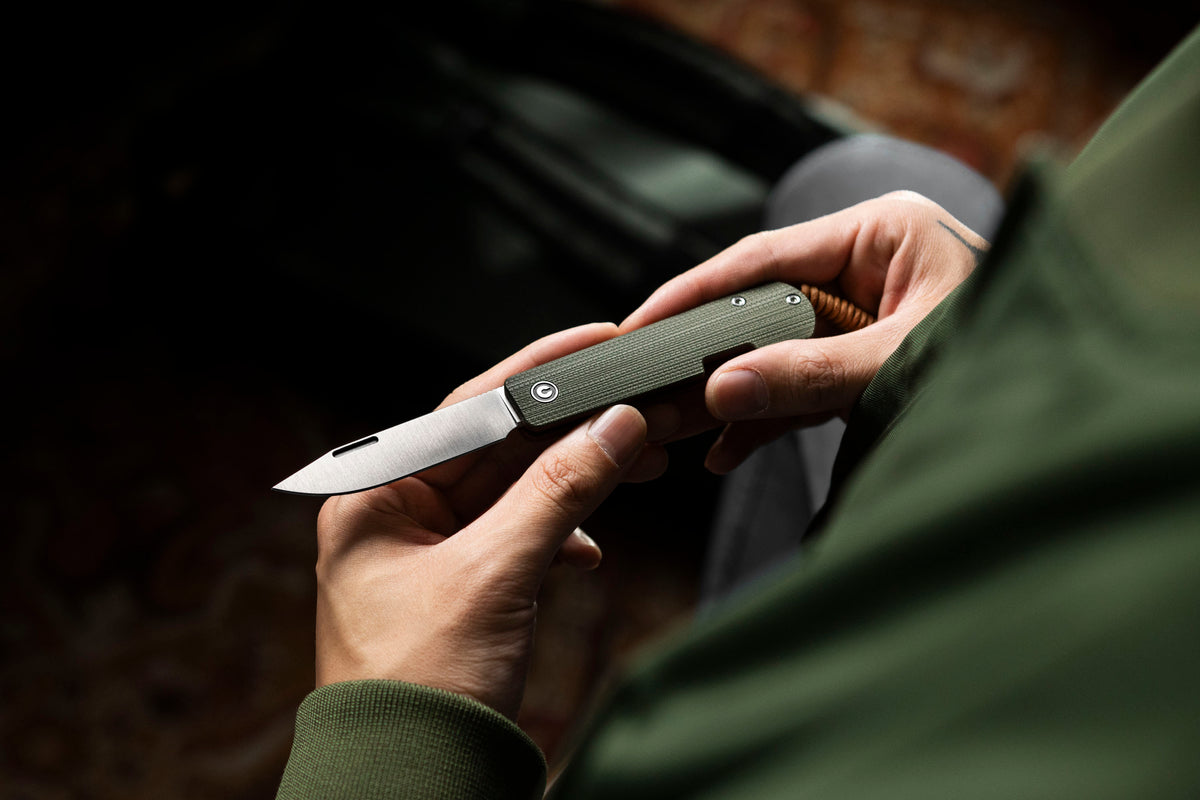 Hand cutting material with open Slippy Sendy pocket knife, green and red handle