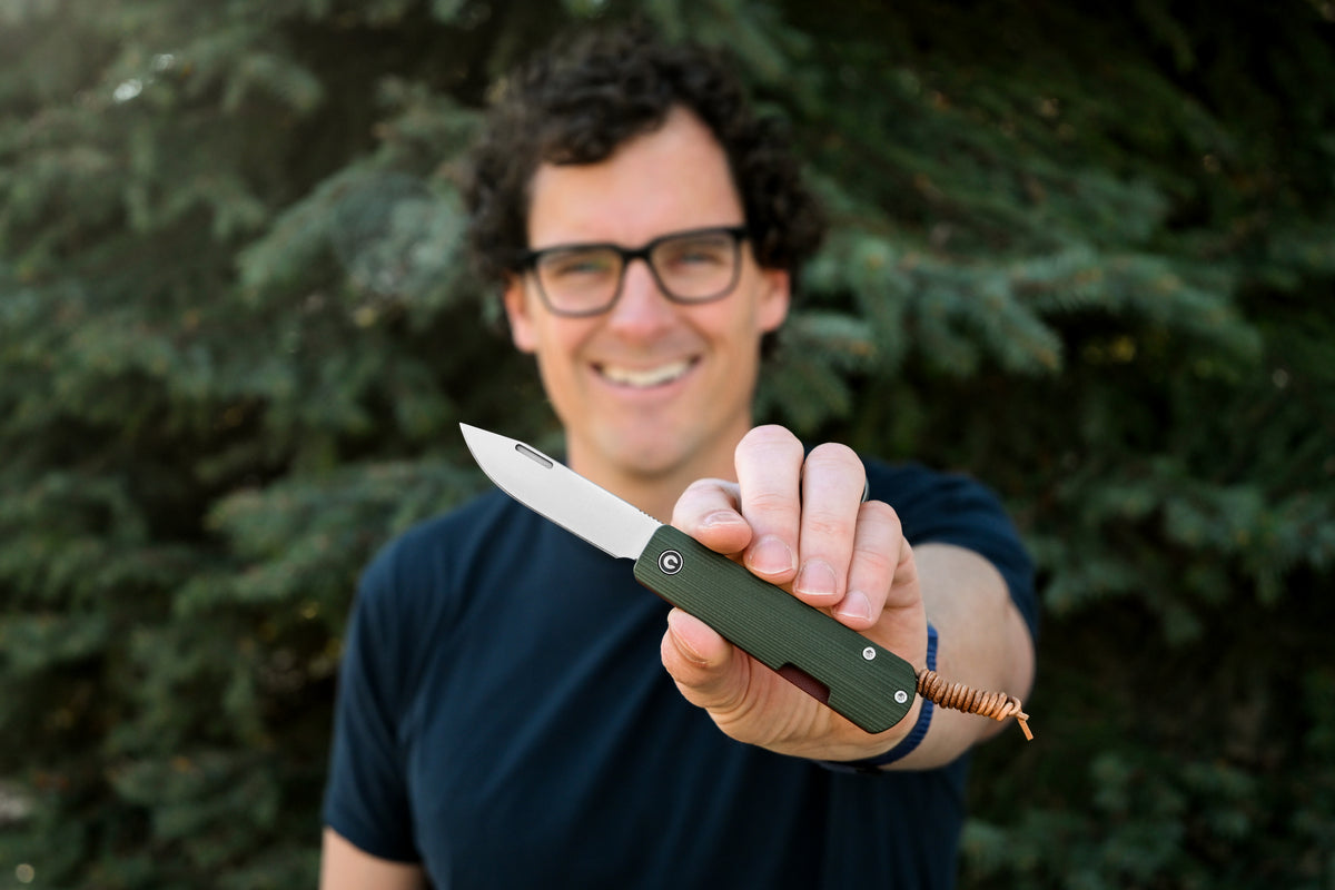Man with glasses smiling and holding open Slippy Sendy pocket knife