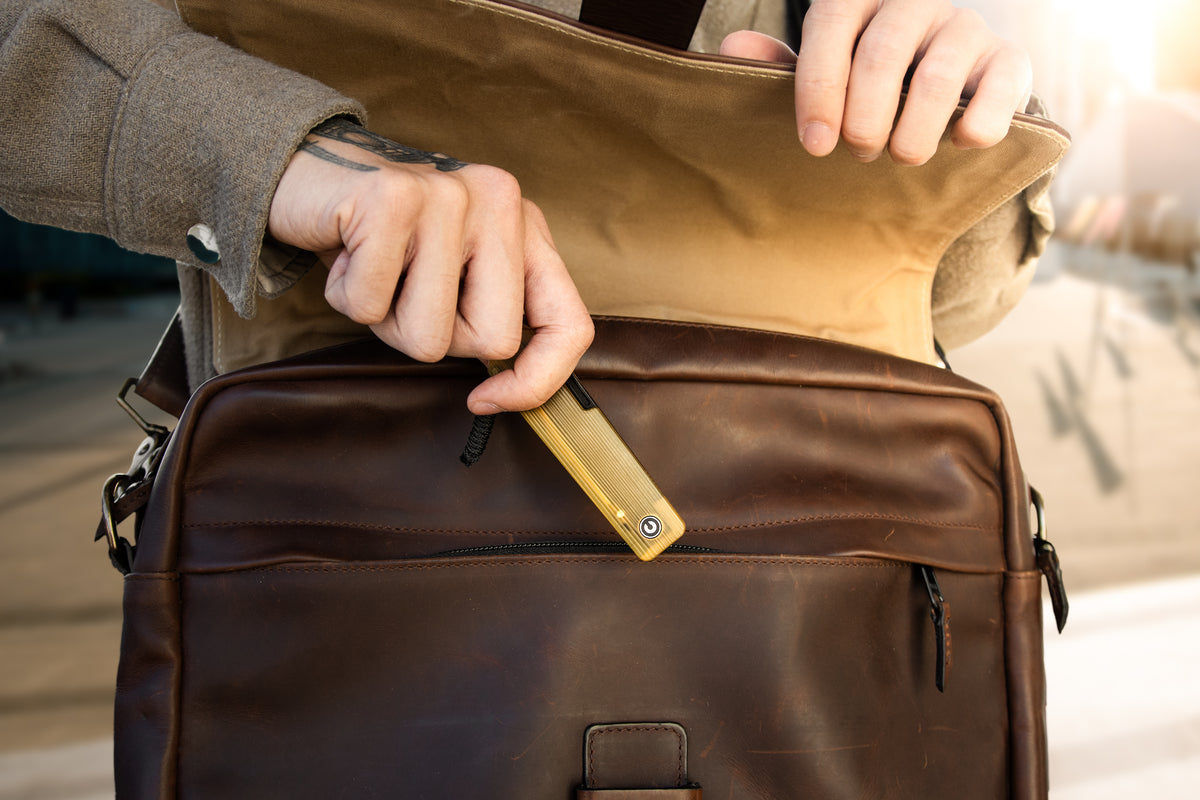 Hand pulling Slippy Sendy pocket knife with tan Ultem handle from leather bag pocket