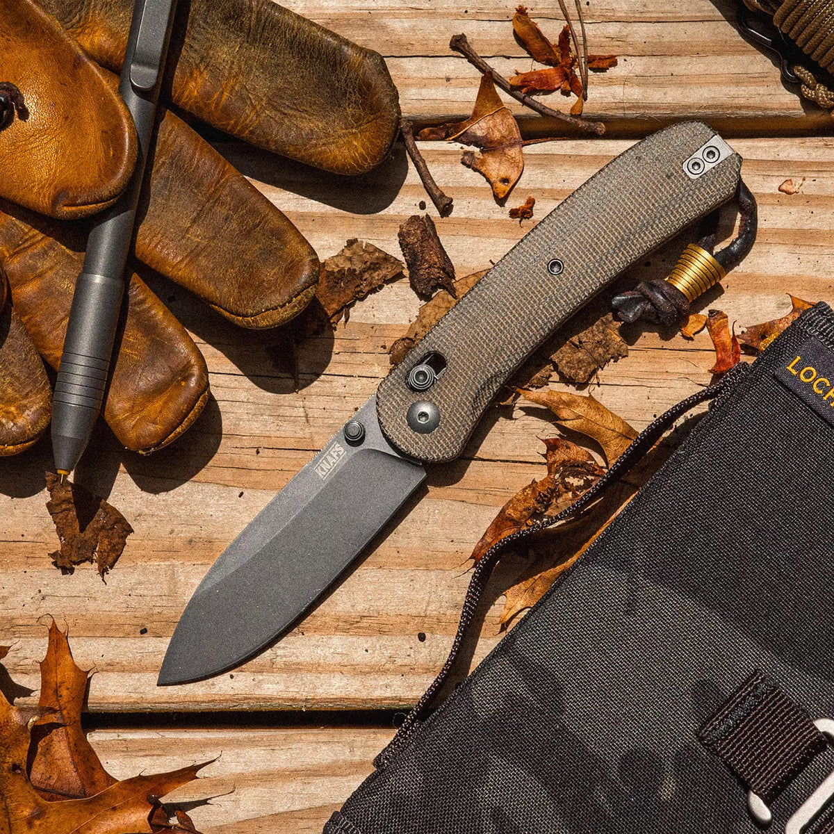 Lander 2 Pocket Knife in Moondust Micarta, closed, lying on a wood table with autumn leaves