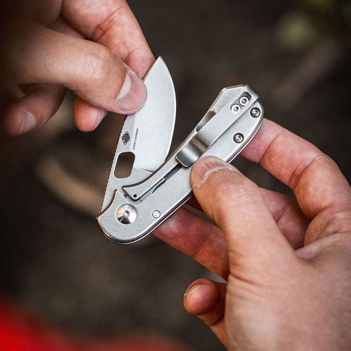 KNAFS-00396 Lander 5 Close-up of hands holding a folding knife with a blurred background