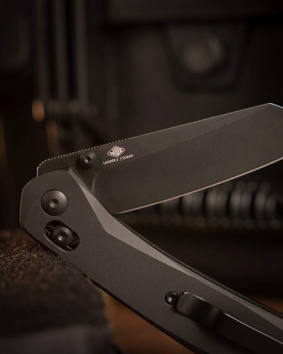 Lander 2 Reverse Tanto pocket knife with black handle resting on rugged outdoor surface