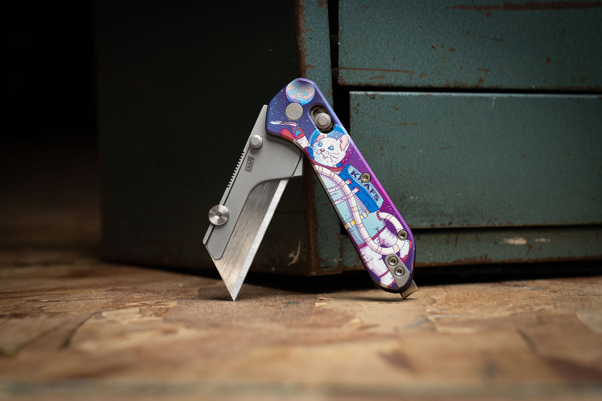 Yuti utility knife with Kitty Cosmo Crew pattern handle standing upright on wood surface