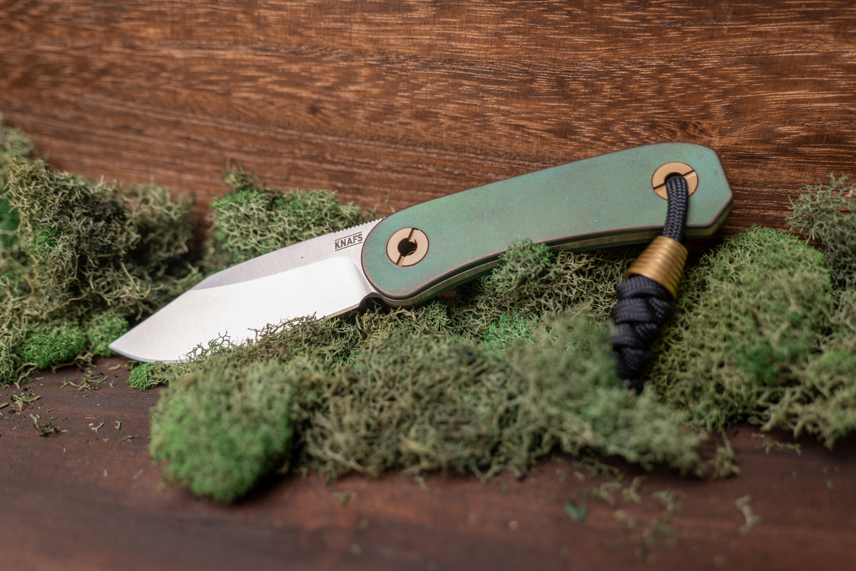 Lander 4 Lady Liberty edition pocket knife, open, resting on wood surface with greenery