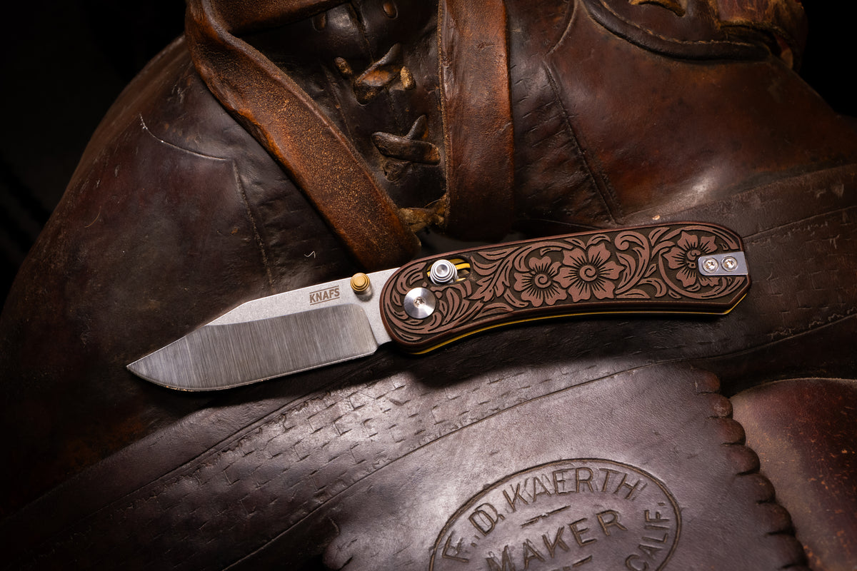 Lander 3 knife, Filigree Western clip point edition, closed, resting on leather saddle
