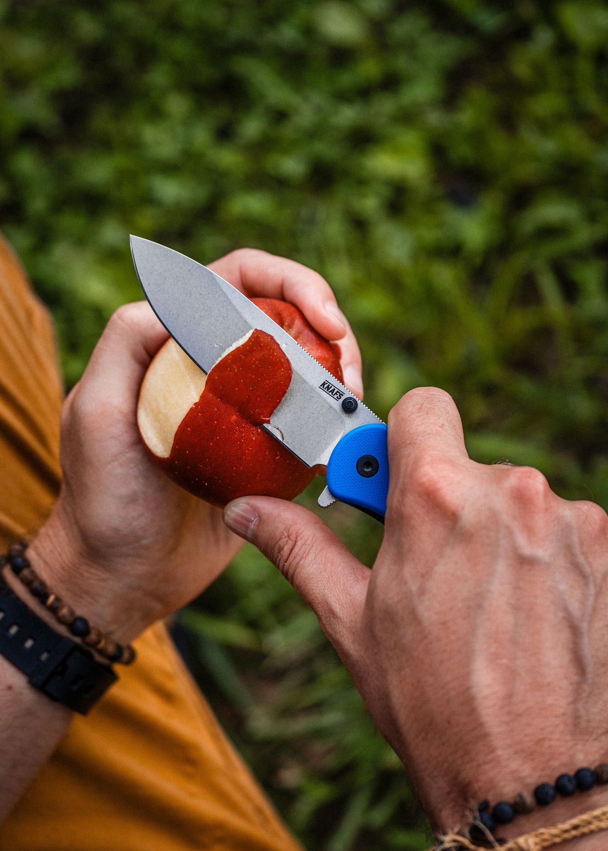 Hand holding Lander 7 pocket knife with blue G10 handle outdoors