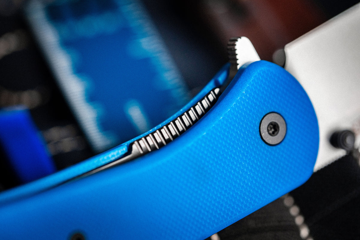 Close-up of Lander 7 pocket knife with blue G10 handle clipped to backpack zipper