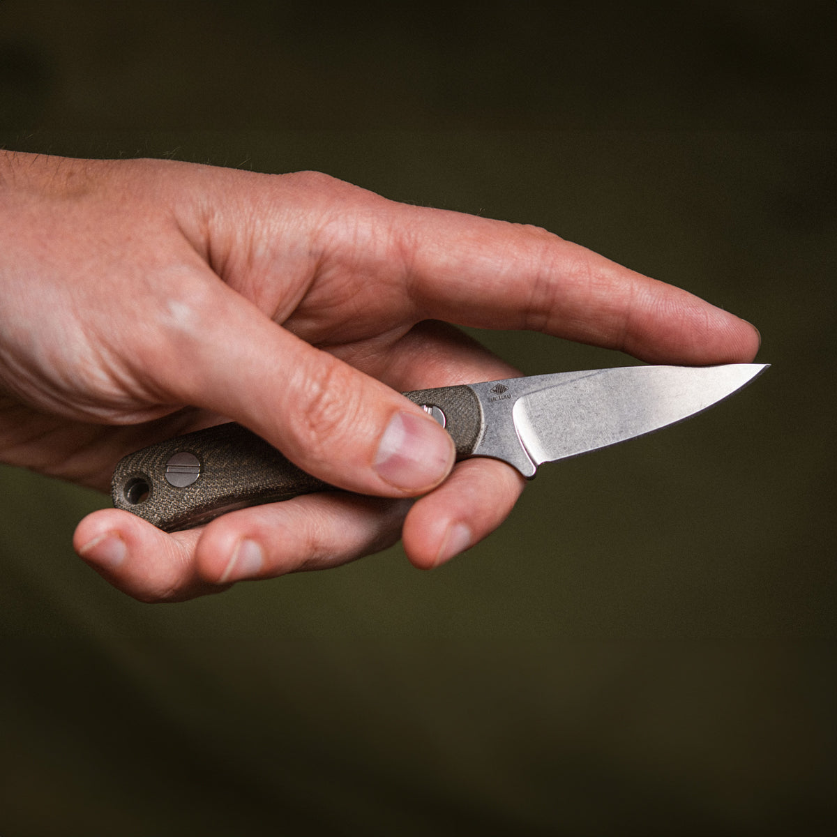 Hand holding Little Lulu stonewashed fixed blade knife, back view