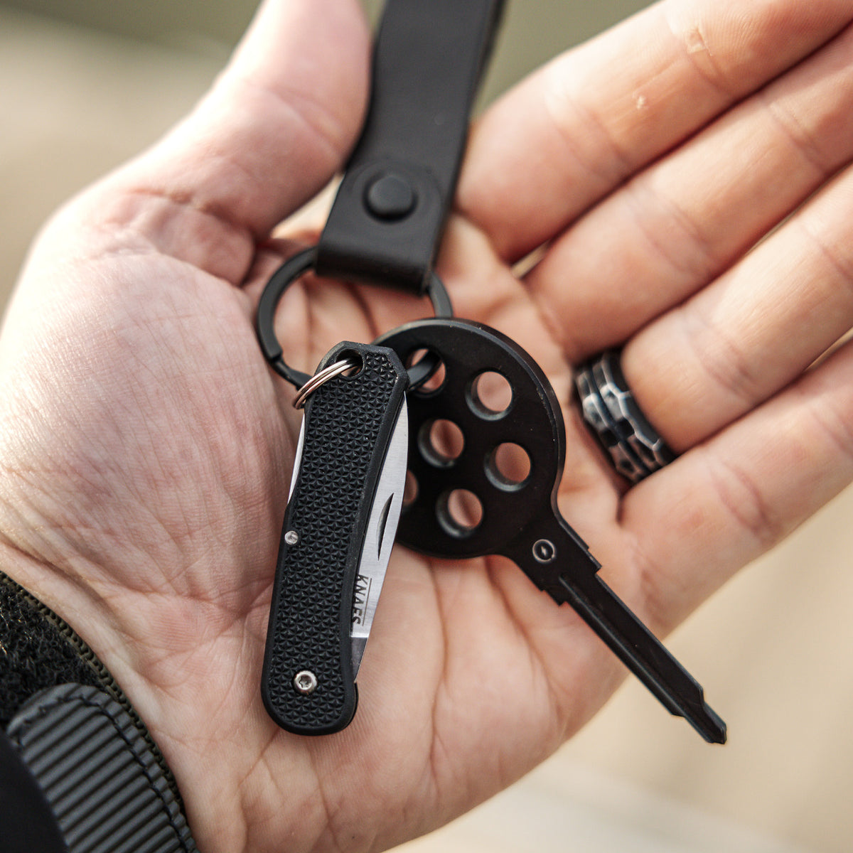 Hand holding a Lander 6 mini keychain knife with keys attached, blade open