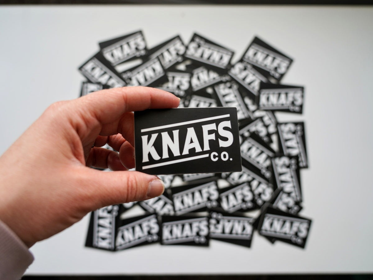 Hand holding several Blackout Knafs Co. stickers fanned out